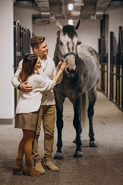 Mand og kvinde i en stald sammen med hest